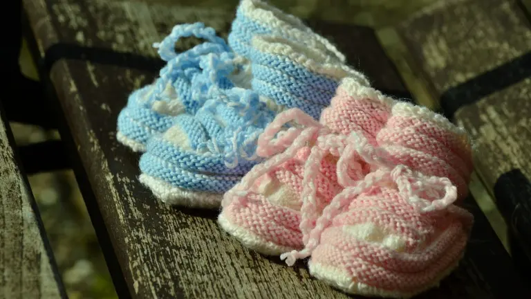 Rosa og blå babysko placeret på en bænk