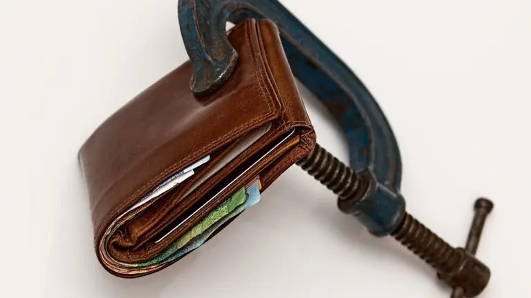 Wallet squeezed in a clamp symbolizing debt