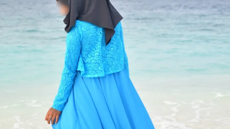 Woman wearing a blue abaya by the sea