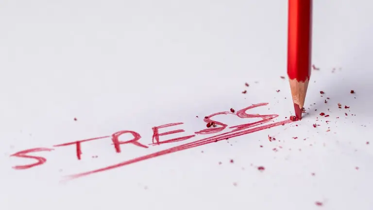 Red pencil erasing the word stress on paper