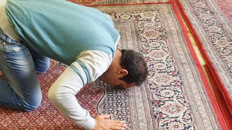 Man prostrating in prayer on a prayer rug