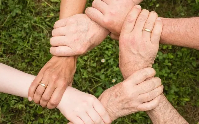 Hænder fra flere generationer samlet i en cirkel