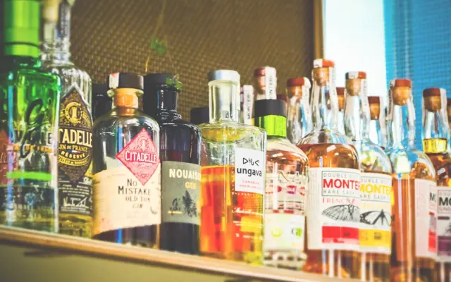 Alkoholipulloja rivissä hyllyllä