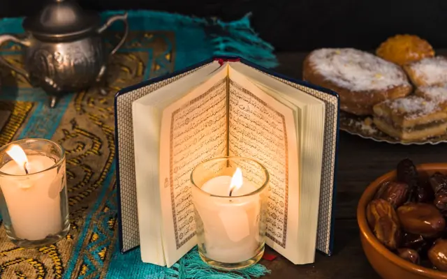Open Quran with candle and dates