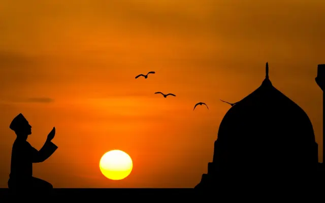 Silhouette of a man making dua at sunset
