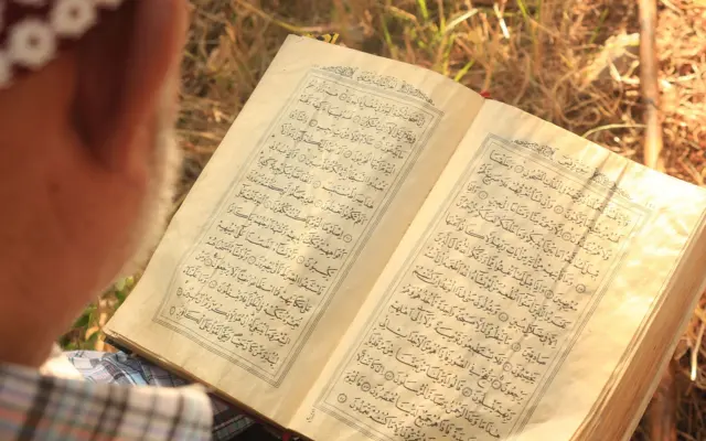 Person reading the Quran outdoors