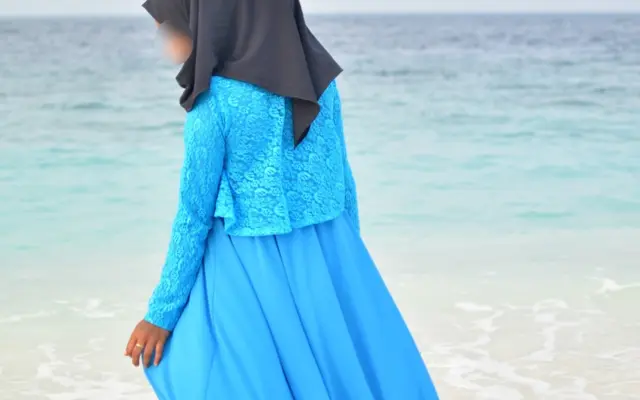 Frau in einer blauen Abaya am Meer