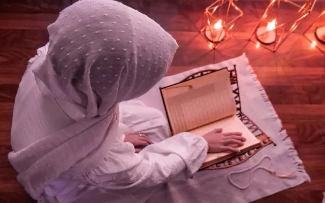 Woman reading the Quran in a prayer space