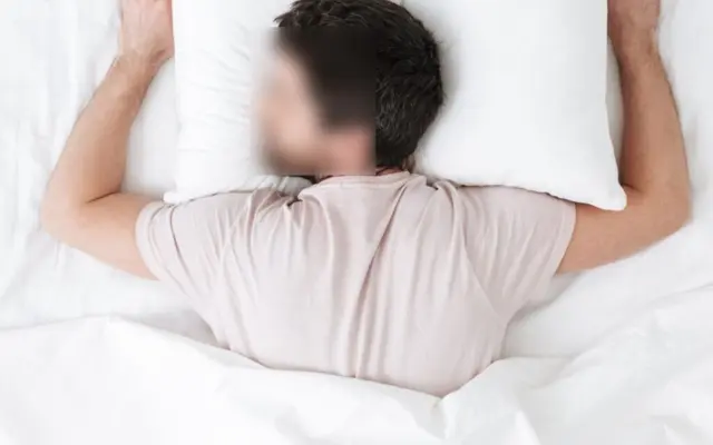 Person, die im Bett auf dem Bauch schläft