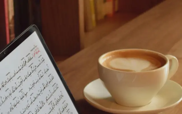 Student som lär sig arabiska online med en surfplatta och en kopp kaffe