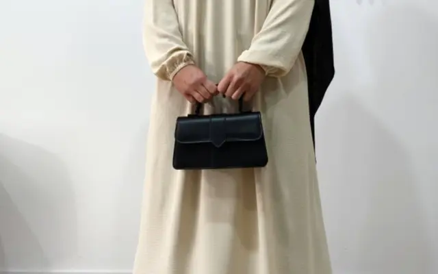 Muslim woman wearing a beige abaya and black khimar
