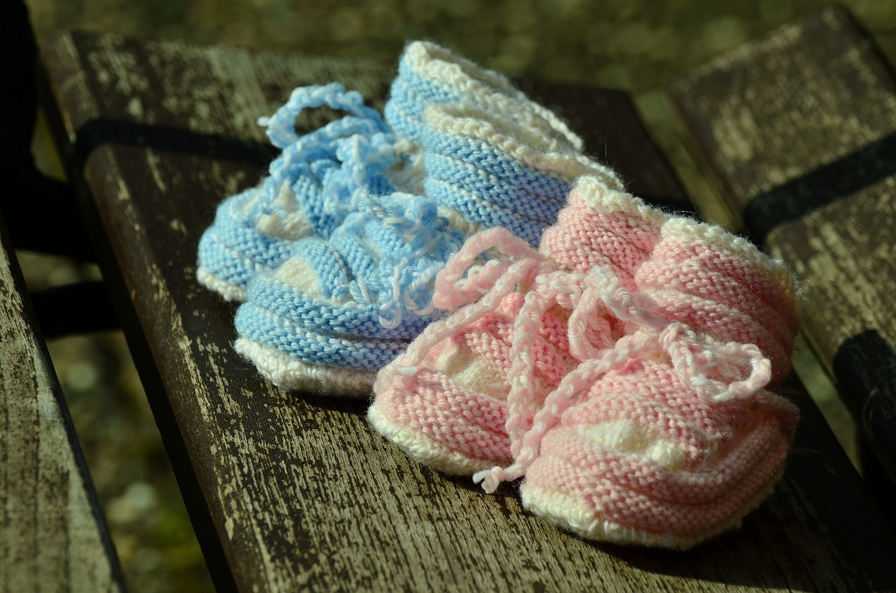 Pink and blue baby booties placed on a bench