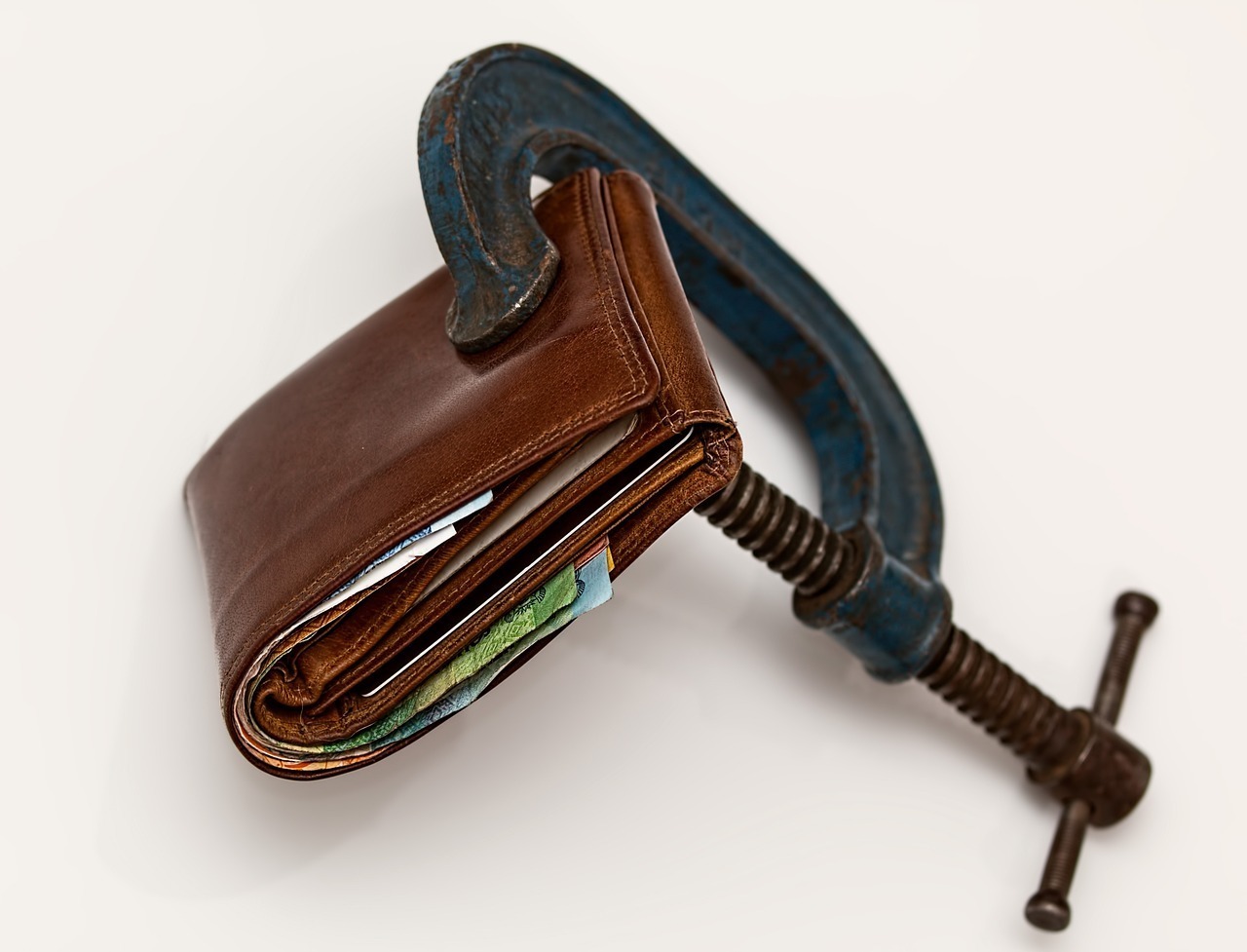 Wallet squeezed in a clamp symbolizing debt