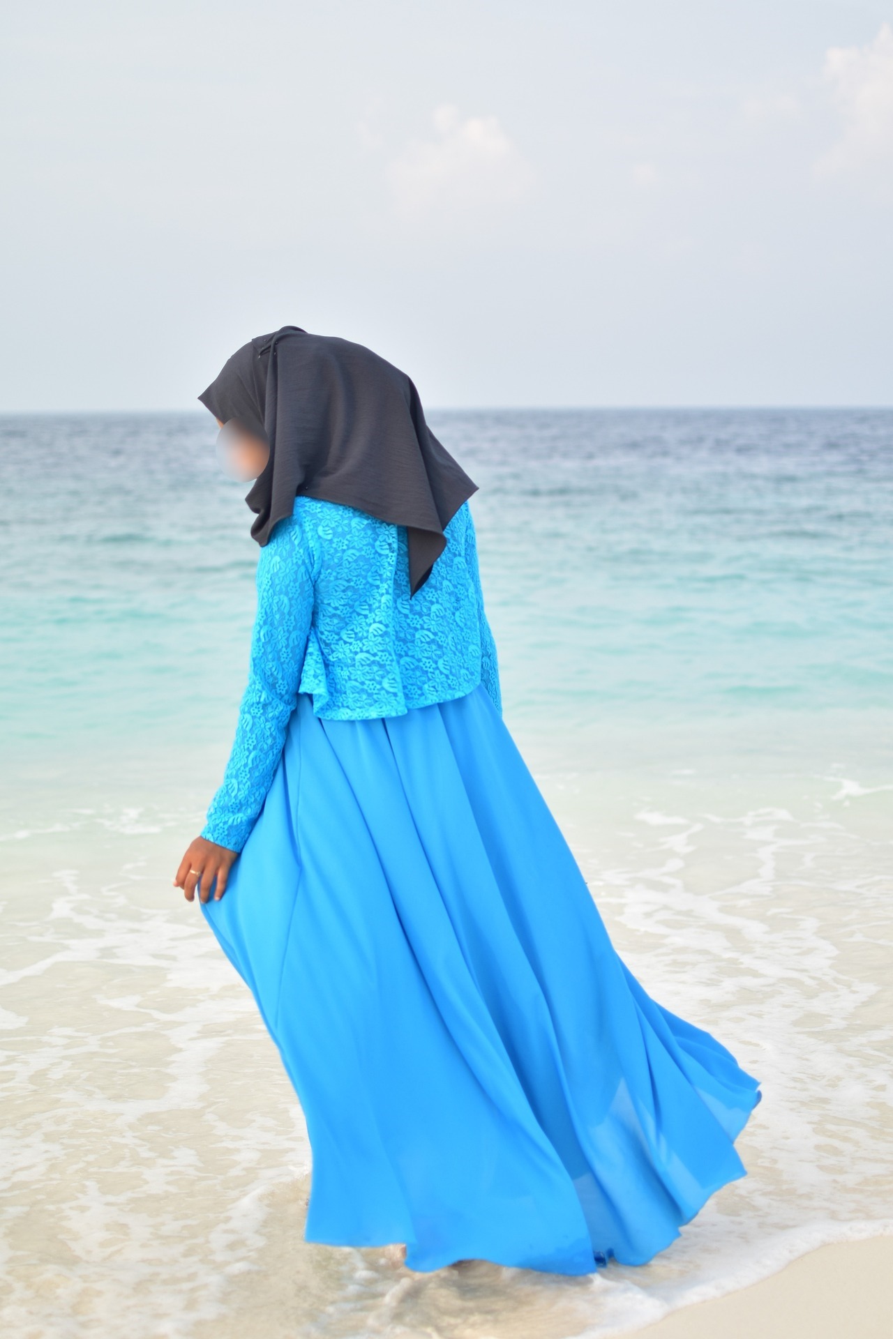 Woman wearing a blue abaya by the sea