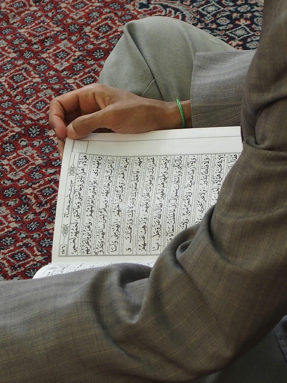 Man reading the Quran on a prayer rug